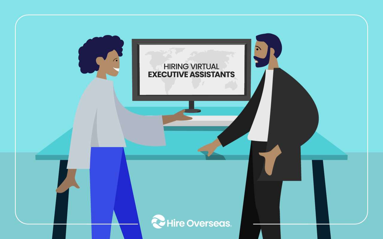 Two people talking at a desk beside a monitor about hiring virtual executive assistants with a world map